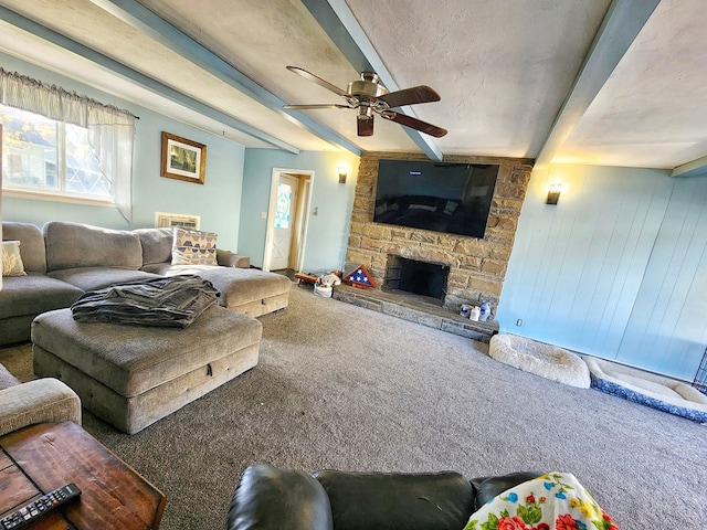 carpeted living room with ceiling fan, a stone fireplace, a textured ceiling, and beam ceiling