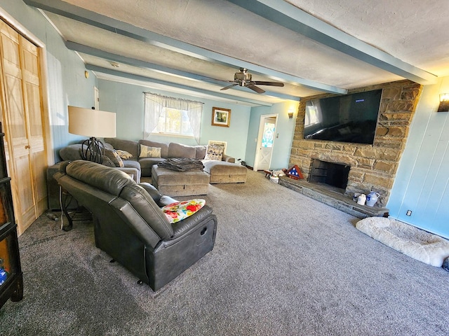 living room with a textured ceiling, dark carpet, beamed ceiling, ceiling fan, and a fireplace