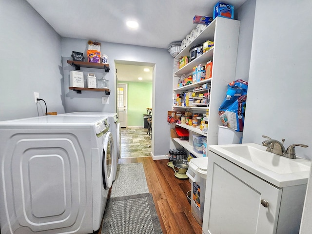 washroom with washing machine and dryer, sink, and dark hardwood / wood-style flooring