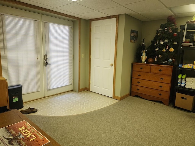 doorway with a paneled ceiling and light carpet