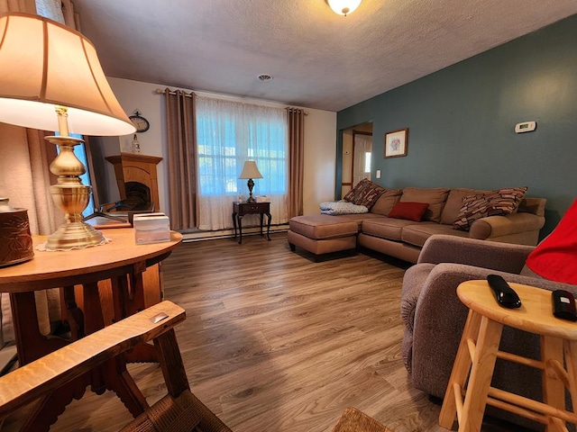 living room with baseboard heating, wood-type flooring, and a textured ceiling