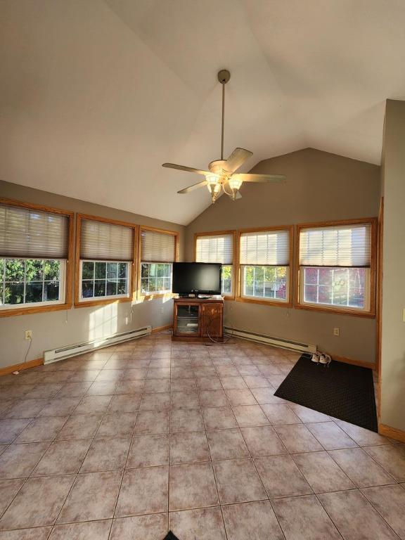 unfurnished living room featuring ceiling fan, a baseboard radiator, vaulted ceiling, and light tile patterned floors