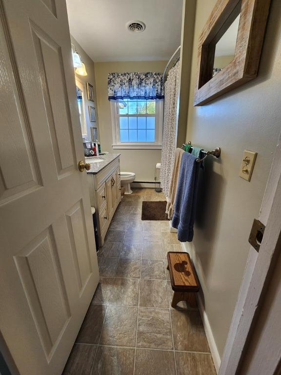 bathroom with vanity, toilet, and a baseboard heating unit