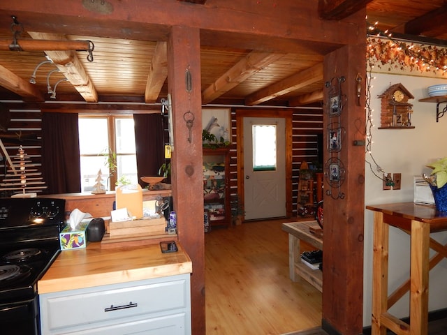 kitchen featuring black range with electric cooktop, light wood-type flooring, beam ceiling, wooden ceiling, and white cabinets