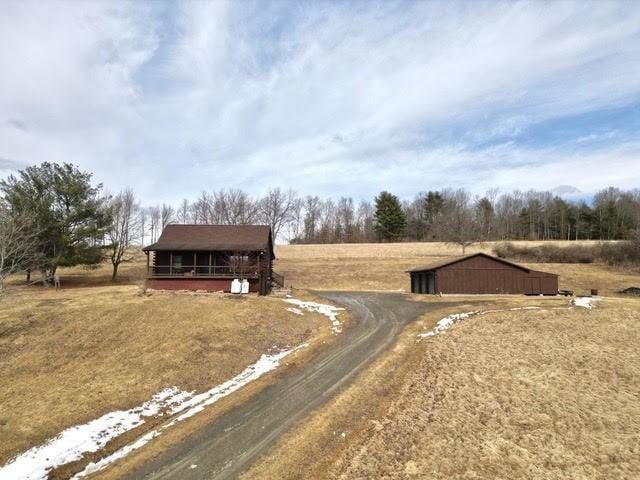 view of front of home featuring a rural view, an outdoor structure, and dirt driveway