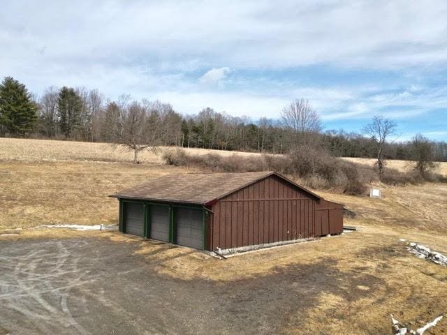 view of outdoor structure with an outbuilding, a rural view, and driveway