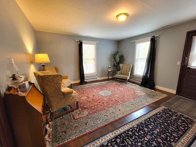 sitting room with a baseboard heating unit, wood finished floors, a wealth of natural light, and baseboards