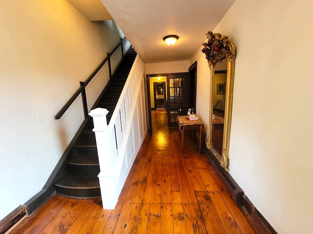 hallway featuring hardwood / wood-style flooring, baseboards, and stairway