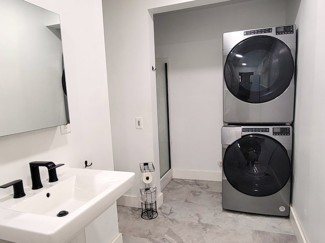 laundry area with stacked washer and clothes dryer, a sink, and baseboards