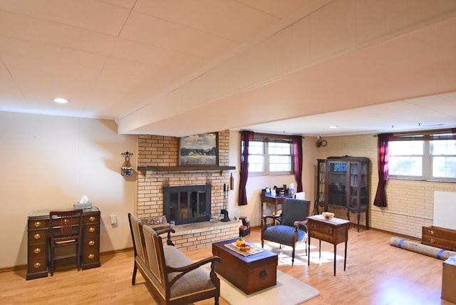 living room with a fireplace, wood-type flooring, and brick wall