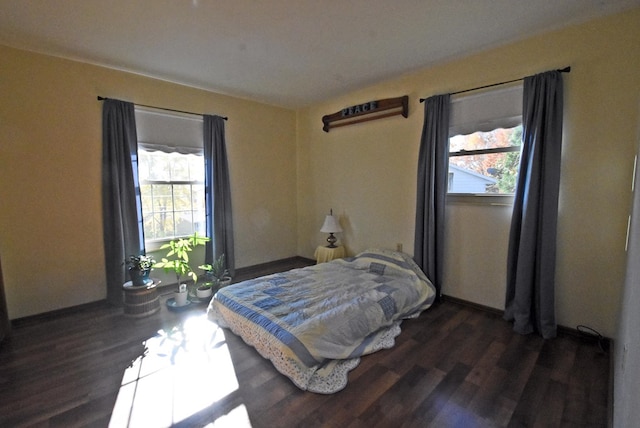 bedroom with multiple windows and dark hardwood / wood-style flooring