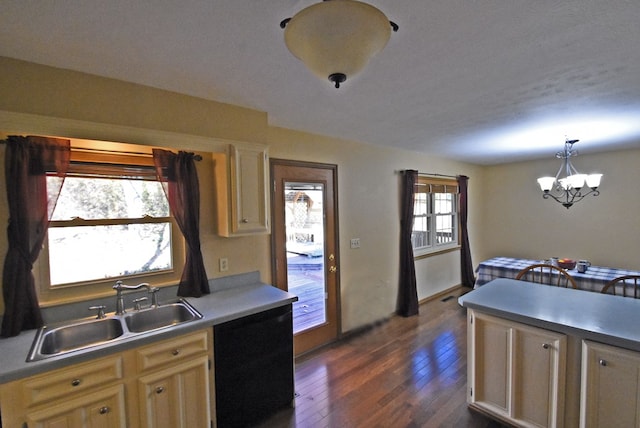 kitchen featuring dark wood-type flooring, sink, hanging light fixtures, black dishwasher, and a notable chandelier