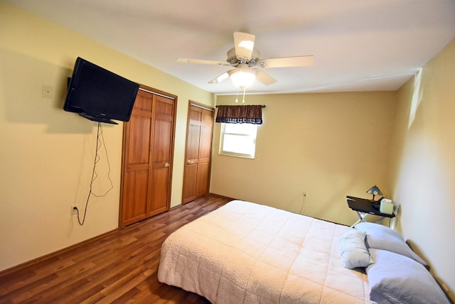 bedroom with dark wood-type flooring, two closets, and ceiling fan