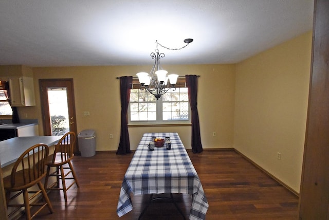 dining room with dark wood-type flooring, a wealth of natural light, and an inviting chandelier