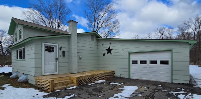 snow covered rear of property with a garage