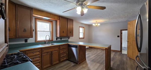 kitchen with pendant lighting, sink, dark hardwood / wood-style flooring, kitchen peninsula, and stainless steel appliances