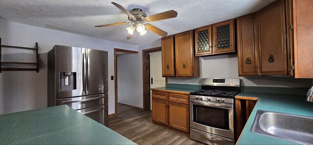 kitchen with stainless steel appliances, sink, a textured ceiling, and dark hardwood / wood-style flooring