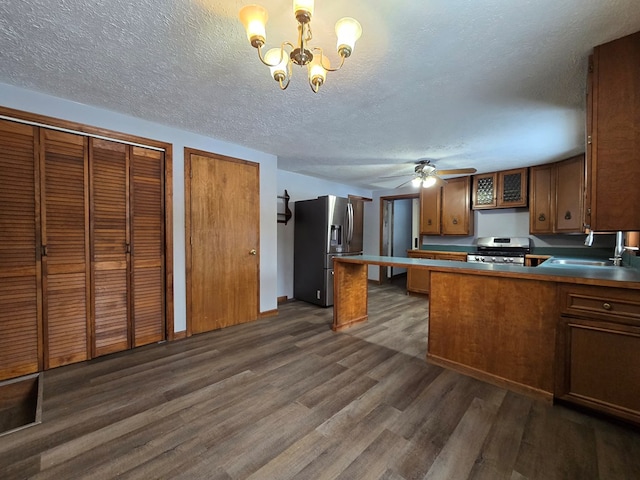 kitchen featuring dark wood-type flooring, sink, appliances with stainless steel finishes, kitchen peninsula, and pendant lighting