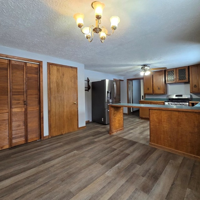 kitchen with appliances with stainless steel finishes, dark hardwood / wood-style floors, decorative light fixtures, kitchen peninsula, and a textured ceiling