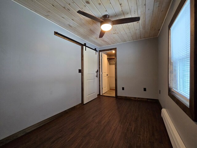 spare room featuring dark wood-type flooring, wood ceiling, baseboard heating, ceiling fan, and a barn door