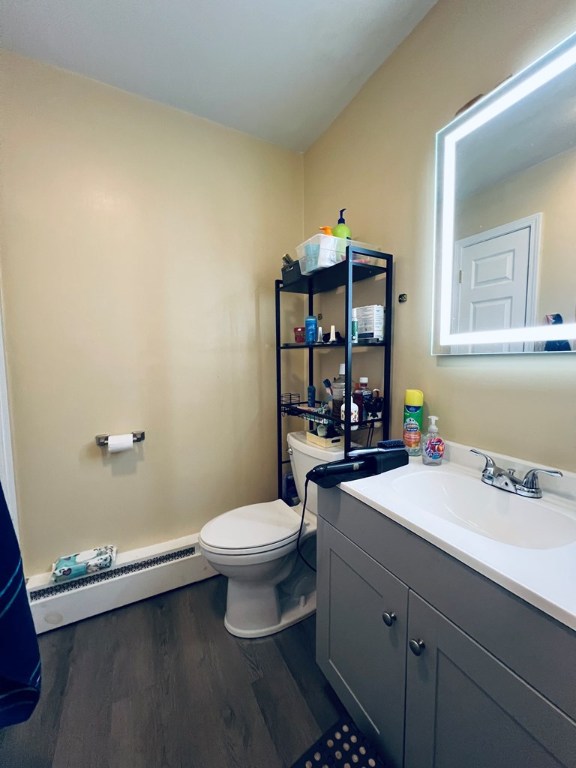 bathroom featuring vanity, toilet, wood finished floors, and baseboard heating