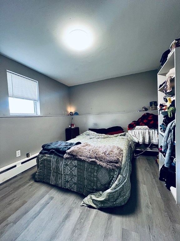 bedroom with a baseboard heating unit and wood finished floors