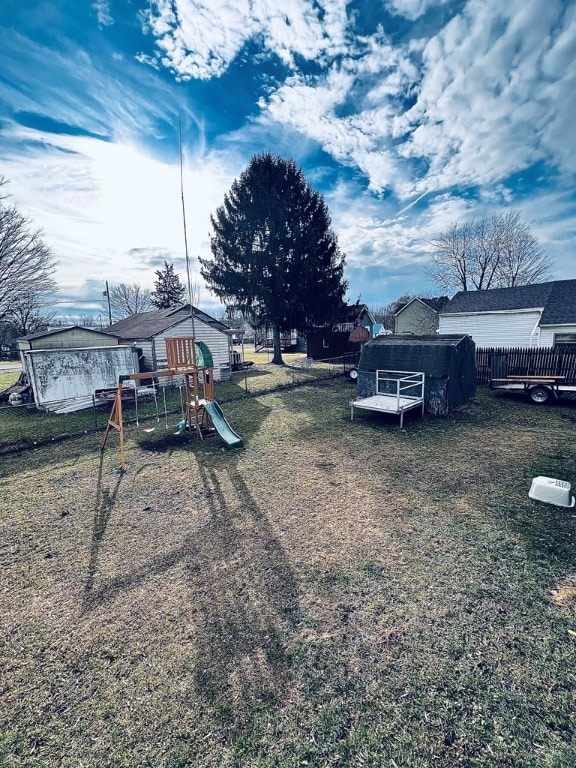 view of yard featuring an outdoor structure, a playground, and fence