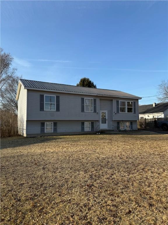 bi-level home with metal roof and a front yard