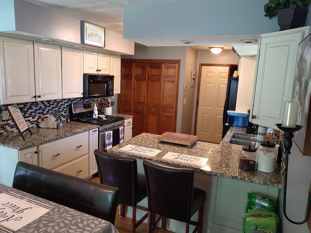 kitchen featuring decorative backsplash, a kitchen breakfast bar, kitchen peninsula, and white cabinets