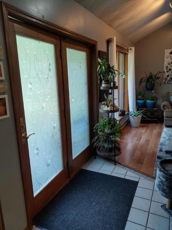 doorway to outside with lofted ceiling and light tile patterned flooring