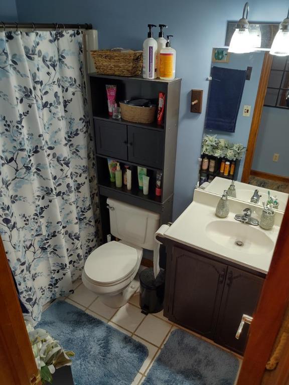 bathroom with vanity, tile patterned floors, toilet, and walk in shower