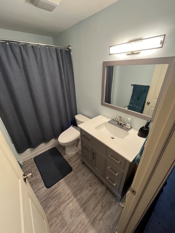 full bathroom with vanity, hardwood / wood-style floors, shower / bath combo with shower curtain, and toilet