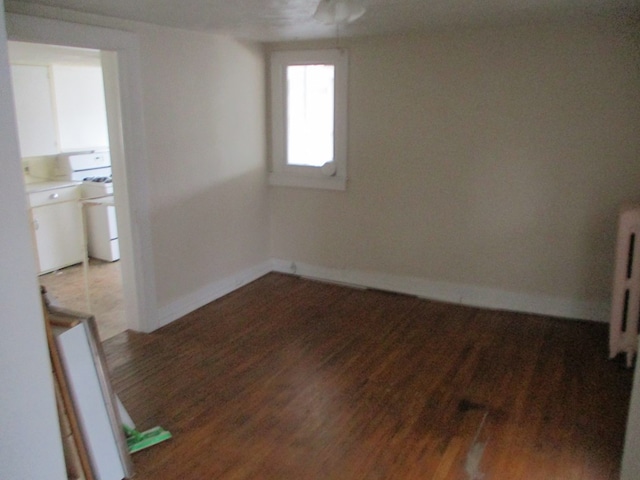 spare room featuring radiator and dark hardwood / wood-style flooring