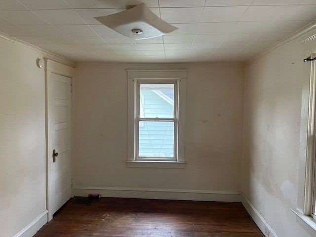 empty room featuring dark hardwood / wood-style flooring and ornamental molding