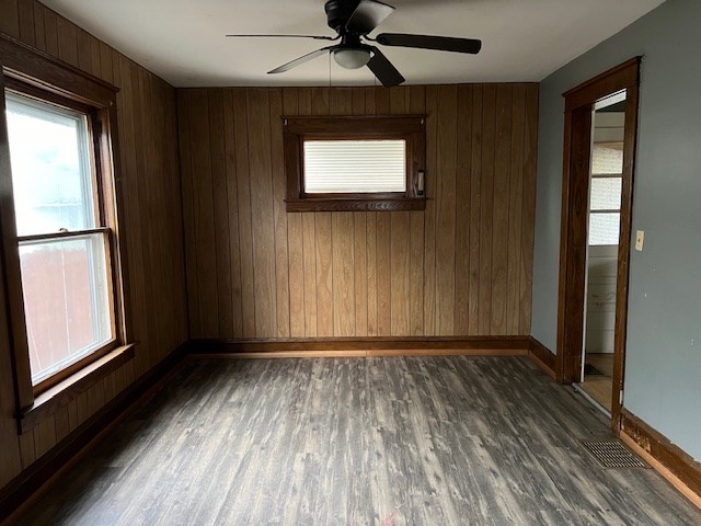 spare room with ceiling fan, wooden walls, and dark hardwood / wood-style floors