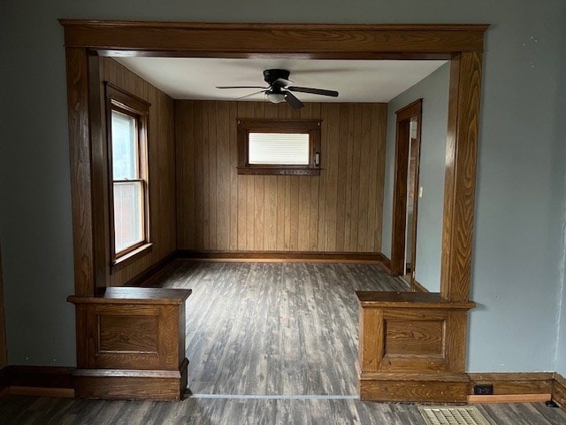 spare room with ceiling fan, dark hardwood / wood-style flooring, and wood walls