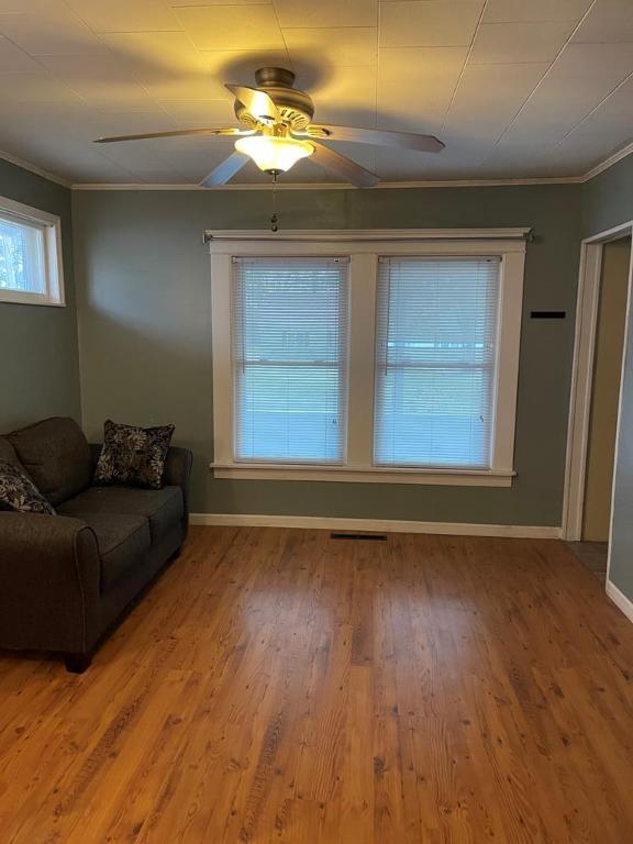 unfurnished living room with hardwood / wood-style flooring, ceiling fan, and ornamental molding