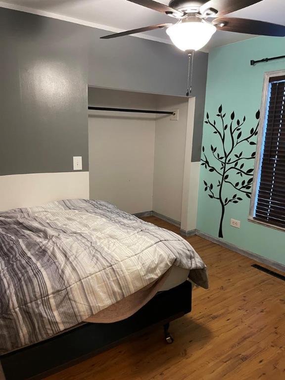 bedroom featuring ceiling fan, wood-type flooring, and a closet