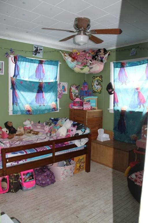 bedroom with ceiling fan, ornamental molding, and wood-type flooring