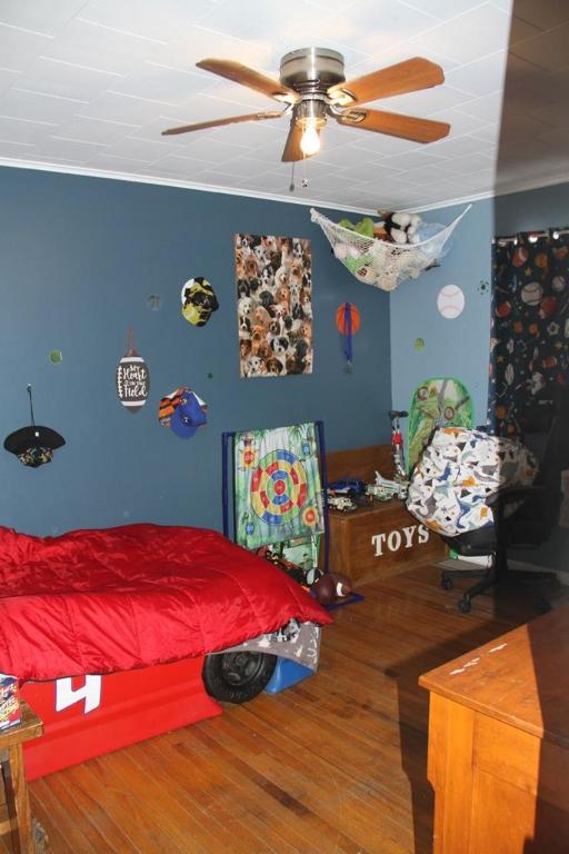 bedroom with ornamental molding, wood-type flooring, and ceiling fan