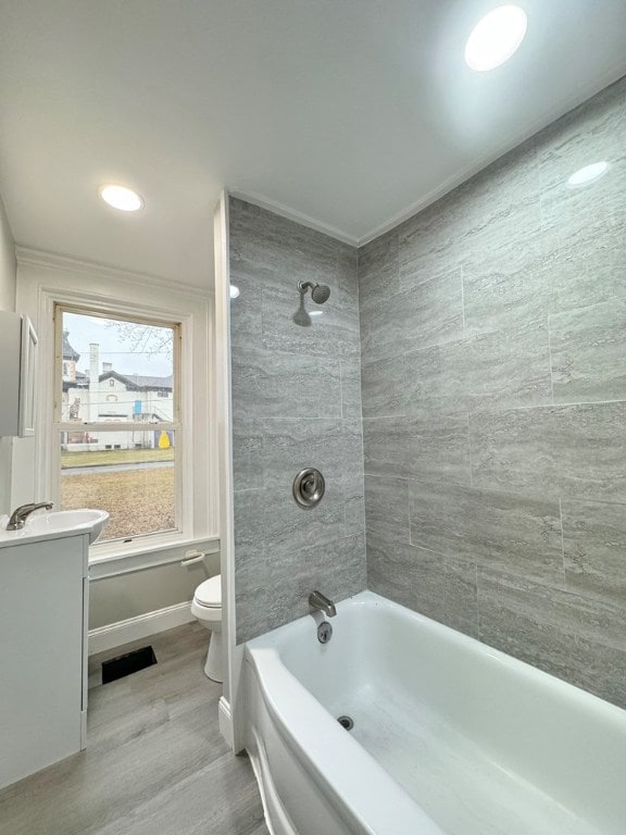 full bathroom featuring vanity, toilet, tiled shower / bath combo, and hardwood / wood-style floors