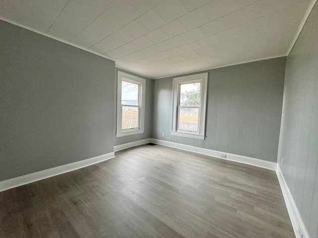 empty room with hardwood / wood-style flooring and crown molding