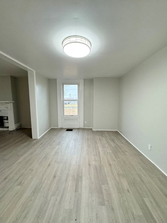 spare room with a large fireplace and light wood-type flooring