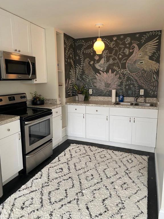 kitchen with sink, appliances with stainless steel finishes, hanging light fixtures, light stone countertops, and white cabinets