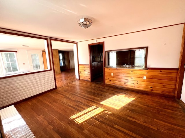 unfurnished room with brick wall and dark wood-type flooring