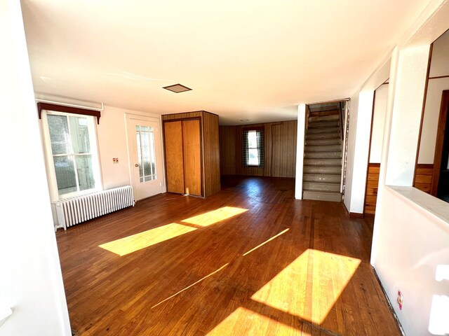 unfurnished room with radiator heating unit, dark hardwood / wood-style floors, and wood walls