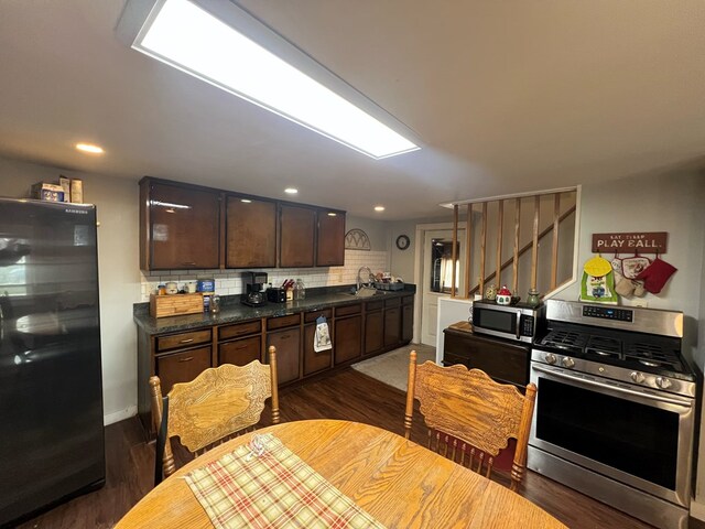 kitchen with appliances with stainless steel finishes, sink, backsplash, dark hardwood / wood-style flooring, and dark brown cabinetry