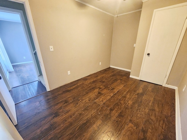 spare room with crown molding and dark wood-type flooring