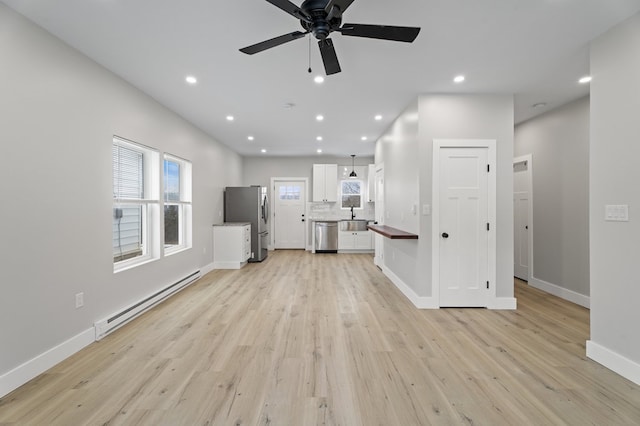 unfurnished living room with ceiling fan, a baseboard heating unit, and light hardwood / wood-style floors