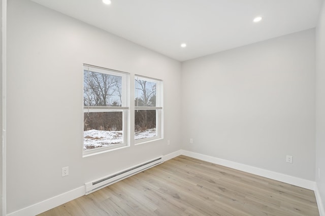 empty room featuring baseboard heating and light wood-type flooring